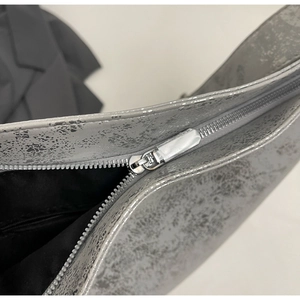 Detailed close-up of metallic silver crackle texture and premium metal zipper on bucket bag