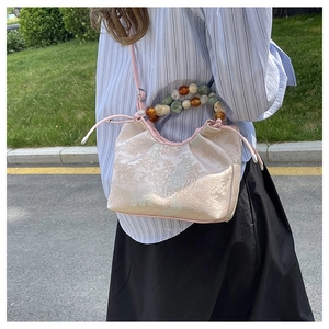 Vue détaillée du sac à main oriental en brocart rose avec une poignée en perles colorées
