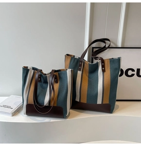 Detail of color-block striped canvas tote bags in green and yellow with leather handles