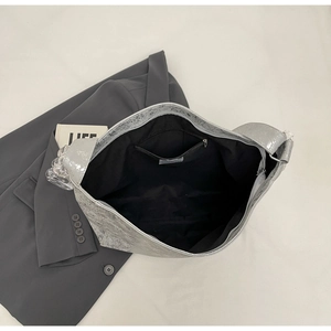 Top view of large silver hobo bag interior showing black lining and zip pocket