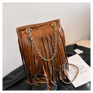 Détail du sac à franges marron avec bandoulière dorée sur une veste en cuir noir