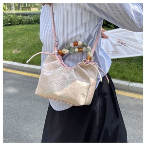 Détail d'un sac seau rose de style néo-chinois avec broderie et anse perlée