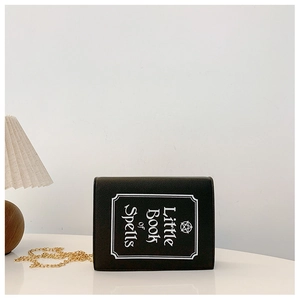 Creative black book-shaped crossbody bag with gold chain and Little Book of Spells print