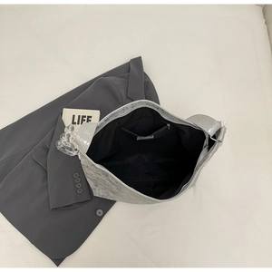 Detail of silver metallic hobo bag showing the spacious black interior and zipper pocket