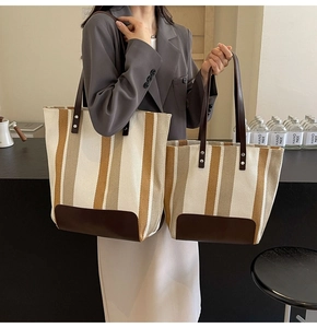 Size comparison of striped canvas tote bags in large and medium with leather straps