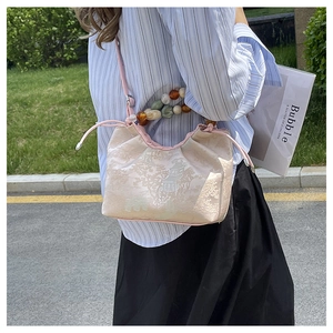 Détail du sac à main de style chinois avec motifs de paysage en soie et poignée perlée