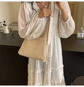Detail of hand-woven beige mesh bag featuring a white leather strap and gold metal buckle