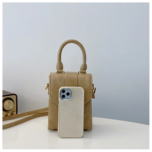 Miniature khaki crossbody bag compared with a smartphone to show its compact small size