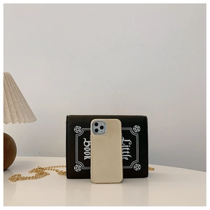 Detailed size comparison of a black punk skull chain bag next to a beige smartphone