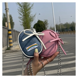Detalle de mini bolsos bandolera redondos con lazo decorativo y cadenas de bolas plata