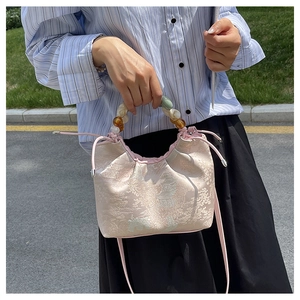 Détail du sac jacquard rose avec motifs de paysages et poignée en perles de résine colorée