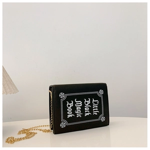 Detail of creative black book-shaped crossbody bag with white Little Black Magic Book print