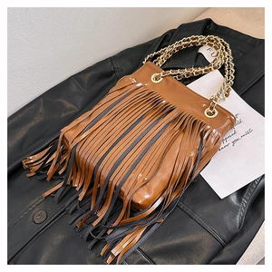 Détail du sac vintage en cuir marron avec de longues franges et chaîne dorée chic