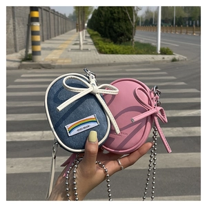 Detalle de minibolsos bandolera con lazos decorativos y cadenas metálicas plateadas