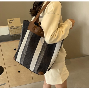Close-up of a large striped canvas tote bag with reinforced brown leather corners