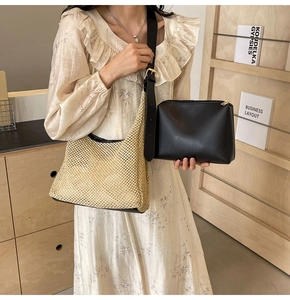 Detail view of woven straw beach bag with black shoulder strap and leather pouch insert