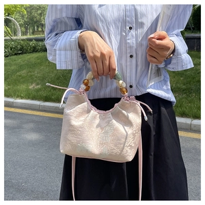 Détail du sac jacquard rose clair avec motif paysage et poignée perlée multicolore