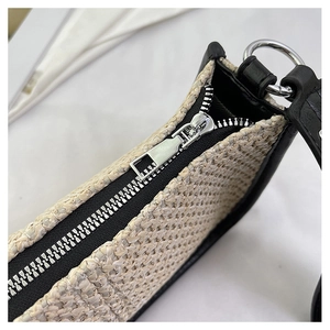 Détail de la paille tressée beige avec bordure en cuir noir et fermeture éclair en métal argenté