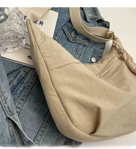 Détail du sac demi-lune beige en nylon montrant la texture du tissu et le curseur tressé