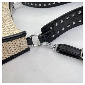 Détail du sac bandoulière en paille tressée avec sangle en cuir noir et rivets argent