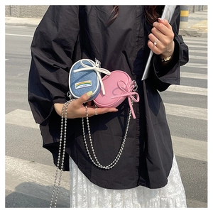 Minibolsos bandolera con detalle de lazo y cadena de bolas metálicas en la calle
