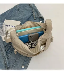 Intérieur spacieux du sac bandoulière en nylon beige montrant la capacité pour tablette et objets