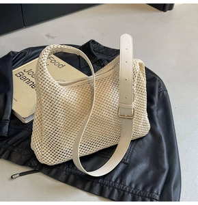 Detail of cream woven shoulder bag featuring adjustable leather strap and gold metal buckle