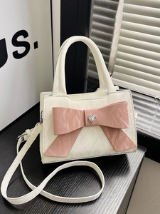 Creamy white handbag with large pink leather bow and heart-shaped rhinestone charm