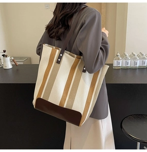 Detail of canvas tote bag with contrast stripes and reinforced brown leather bottom base