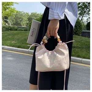 Détail du sac jacquard rose clair avec poignée en perles colorées et bandoulière amovible