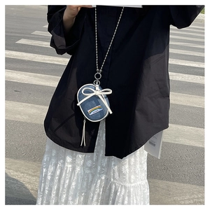 Detalle de mini bolso bandolera vaquero con lazo blanco y correa de cadena de bolas plata