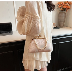 Detail of a pink jacquard cheongsam bag with pearl clasp and chain in an elegant setting