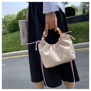 Détail du sac à main en jacquard rose avec poignée en perles colorées et cordon de serrage