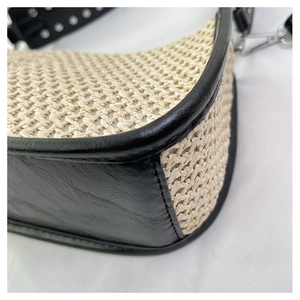 Détail du sac en paille tressée avec coutures en cuir noir et rivets argentés