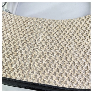 Détail du tissage beige avec bordure en cuir noir et anneau métallique argenté brillant