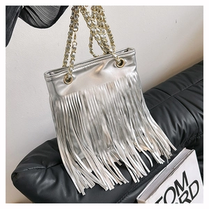 Détail du sac à franges argentées montrant des pompons et une bandoulière dorée