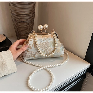 Macro detail of Chinese vintage evening bag with pine embroidery and pearl clasps
