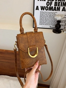 Retro brown leather mini crossbody bag with gold U-buckle shown in a lifestyle scene