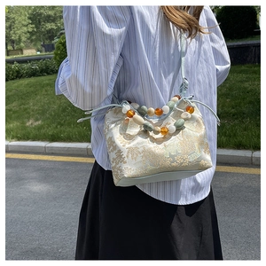 Détail de la broderie florale et poignée perlée sur un sac bandoulière chinois