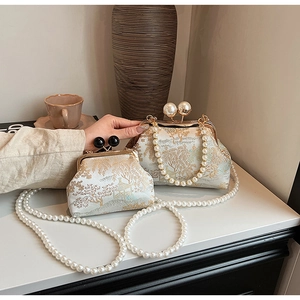Detailed view of vintage-style embroidered bags with gold landscape and pearl clasp accents