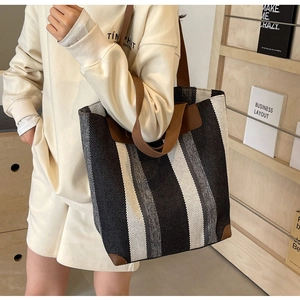 Vertical striped canvas tote bag detail with brown leather trim and handle texture