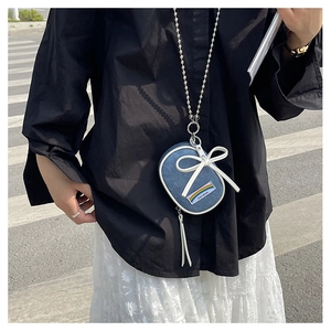 Vista de detalle del mini bolso denim azul con lazo blanco y correa de cadena de plata