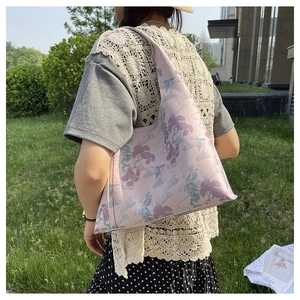 Detailed close-up of pink jacquard tote bag with floral embroidery and red hand-stitched seams