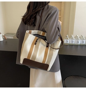 Detail view of large canvas tote bag with contrast vertical stripes and brown shoulder straps