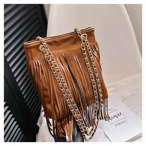 Détail d'un sac à franges marron caramel avec bandoulière chaîne dorée et texture cuir lisse