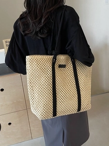 Large beige woven tote bag with black rope handles for beach vacation and daily commute