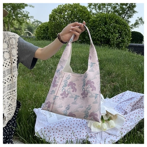 Pink floral hobo bag on a picnic blanket with tulips and greenery in a garden setting