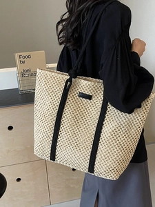 Minimalist cream woven straw tote bag with black straps for beach vacation and casual use