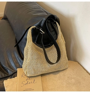Detail of light beige woven straw tote bag with black leather strap and silver metal buckle