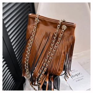 Détail d'un sac seau marron foncé avec de longues franges et des anses dorées
